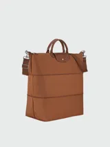 Bolso de viaje ampliable Longchamp modelo Le Pliage Original, color marrón, con diseño de nylon, asas cortas de cuero y correa de hombro ajustable y extraíble. Cuenta con cierre de cremallera y solapa con botón a presión.