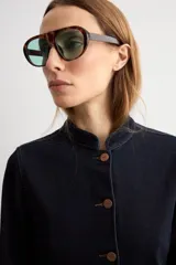 Chaqueta de jean azul oscuro, con cuello mao, cierre frontal de botones metálicos y dos bolsillos frontales de parche.