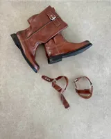 Bota de cuero vacuno color marrón, estilo motociclista o biker, con caña media y hebillas ajustables en el empeine y la caña.