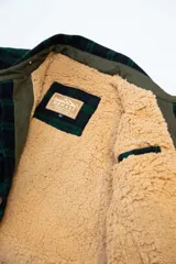 Campera de tartán grueso forrada con corderito marrón, con cuello camisero, cierre con botones, dos bolsillos frontales en el pecho y dos bolsillos para las manos.