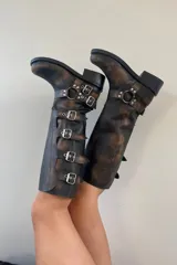 Botas de cuero marrón con efecto gastado, caña alta y hebillas metálicas.