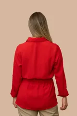 Camisa de seda color celeste, con cuello camisero, mangas largas y lazo ajustable en la cintura que genera un efecto fruncido.