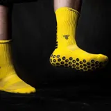 Medias deportivas de caña alta color amarillo, con suela antideslizante que presenta un patrón de círculos negros con el logo de la marca. Incluye logo bordado en la parte superior del empeine.