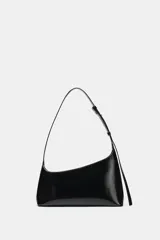 Bolso de hombro de diseño asimétrico en color negro, con acabado brillante de charol, asa ajustable y cierre de cremallera.