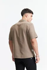 Camisa de manga corta color crema con textura, cuello clásico y calce regular.