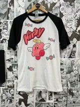 Remera blanca con mangas raglán negras y estampado de Kirby con alas y aureola, rodeado de caramelos. Estilo animé.