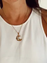 Collar de cadena fina con dije de luna creciente decorada con estrellas pequeñas, en acero quirúrgico dorado.