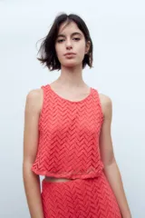Blusa de encaje coral sin mangas con patrón geométrico.