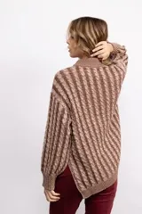 Sweater de tejido de punto con diseño de trenzas verticales, cuello alto, manga larga y silueta oversize de largo extendido.