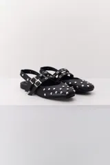 Balerina negra de cuero con punta fina y dos correas marrones con hebilla sobre el empeine. Decorada con tachas plateadas.