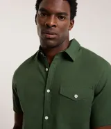 Camisa comfort masculina de lino y algodón color marrón, con cuello inglés, mangas cortas con vuelta, cierre frontal por botones y un bolsillo en el pecho.