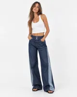 Jean wide leg de tiro medio, confeccionado en denim azul oscuro con paneles laterales en tono denim más claro. Cuenta con diseño de doble botón en la pretina, bolsillos delanteros y corte amplio en las piernas.