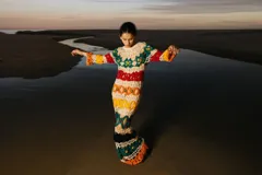 Vestido largo tejido a crochet con diseño calado y rayas horizontales de colores: blanco, verde, rojo, naranja, amarillo, negro y naranja.