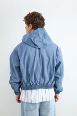 Chaqueta con capucha color celeste de lona pesada, con cierre frontal y bolsillo con cierre en el pecho.