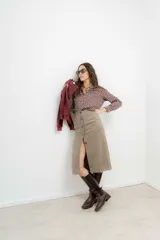 Falda midi de tiro alto confeccionada en tejido tweed con patrón de espiga en tono marrón. Presenta un diseño recto y cierre frontal con botones.