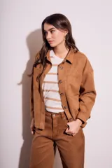 Sobrecamisa negra de estilo shacket, confeccionada en tejido de gamuza sintética. Presenta cuello camisero, cierre frontal de botones y dos bolsillos de parche con solapa en el pecho. El calce es oversize y las mangas son largas.