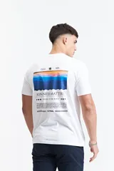 Remera de manga corta color azul marino con cuello redondo y calce regular. Presenta un estampado gráfico en la espalda que incluye un paisaje montañoso al atardecer, el texto 'KINDNESS MATTERS' y el logo de la marca Mistral.