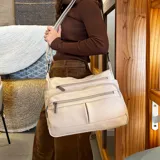 Bandolera de símil cuero color beige, con tres bolsillos frontales con cierre, un bolsillo trasero con cierre y bolsillos internos. Cuenta con una correa larga regulable.