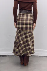 Falda midi de corte evasé con estampado de cuadros escoceses en tonos marrones y beige. Presenta un diseño asimétrico en el ruedo y cierre lateral.