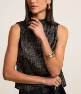 Blusa sin mangas de poliéster satinado color negro con estampado geométrico de líneas blancas y cuello alto drapeado.