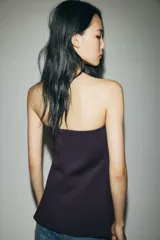 Top strapless de punto roma en color negro, con diseño entallado y cierre frontal de botones dorados, presentando un sutil corte acampanado en el bajo.