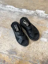 Sandalias negras de cuero con plataforma, tiras cruzadas y hebilla lateral.