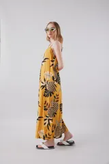 Vestido largo amarillo con estampado de hojas de palmera en blanco y negro, con breteles finos y botones en el frente.