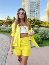 Shorts de cuero color coral, tiro alto, con bolsillos laterales y cierre frontal con botón.