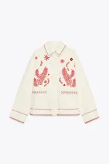 Sobrecamisa color crudo de Zara Woman Collection, con cuello solapa y manga larga. Tiene bolsillos de parche en el delantero y bordados combinados a contraste en color rojo. Cierre frontal con botones a presión ocultos.