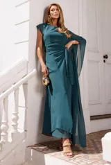 Vestido largo de fiesta color verde petróleo, confeccionado en tela fluida con transparencias. Presenta un diseño de un solo hombro con manga larga tipo capa, ajuste en la cintura con lazo lateral y falda con caída suave.