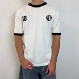 Remera tejida blanca con cuello y puños negros, con el número 10 estampado en la espalda en color negro. Incluye las siglas VCP y el rango de años 2015-infinito.