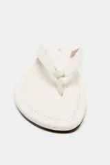 Sandalia plana de piel en color blanco, con tiras delanteras separadoras de dedos y detalle de nudo.