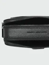 Cartera tipo crossbody Marc Jacobs modelo The Snapshot, color negro con acabado monocromático. Presenta el logo metálico frontal, doble compartimento con cierre y correa ajustable de tela.