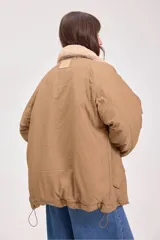 Campera acolchada reversible con capucha, diseño de matelassé, cierre frontal y puños elásticos. Presenta un lado en color verde oliva y otro en color beige.