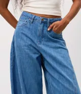 Pantalón de jean estilo aladín con tiro medio, cintura con pasadores, cierre frontal con botón y bolsillos funcionales. Presenta un calce amplio con diseño tipo globo y terminación ajustada en los puños.