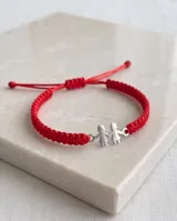 Pulsera de hilo rojo trenzado en macramé, con dije central de plata 925 con diseño de dos nenas tomadas de la mano y cierre regulable.