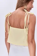 Top amarillo pálido con escote en V, breteles finos con lazos en los hombros y corte holgado con frunce y lazo ajustable en el centro del busto.