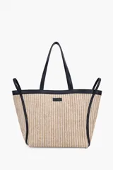 Bolso tipo tote de rafia en tono beige, con detalles en cuero sintético negro en los bordes, asas de hombro y correas decorativas laterales. Incluye un pequeño parche con el logo de la marca en la parte frontal.