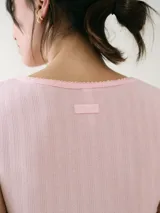 Remera de manga corta color blanco con textura pointelle, corte entallado y cuello redondo con detalle de borde sutilmente ondulado.