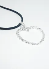 Collar con cordón negro y dije plateado con forma de corazón trenzado.