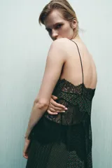 Top estampado con diseño geométrico en tonos verdes y marrones, confeccionado en viscosa 100%. Presenta escote en pico, tirantes finos y detalle de encaje negro a contraste. El bajo tiene un acabado asimétrico.