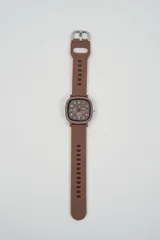 Reloj análogo con caja cuadrada de bordes redondeados y correa de silicona color café. La esfera es negra con números blancos y manecillas blancas. Posee tres subesferas decorativas.