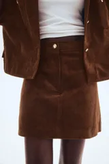 Pollera mini de pana marrón, corte evasé, con cierre y botón frontal.