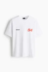 Remera blanca de corte holgado con hombros caídos y cuello redondo. Presenta estampado pequeño de NASCAR y el número 94 en el pecho.