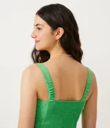 Top cropped de mujer color verde lima, estilo musculosa con escote cuadrado y tirantes. Presenta un lazo ajustable en el centro del busto y un fruncido delantero, con un recorte tipo corset en la parte inferior. La espalda es ajustada con látex.