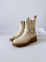 Botas cortas color crudo de cuero, con cierre lateral, pulsera desmontable y suela marrón.