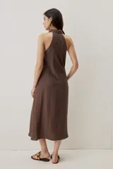Vestido midi color marrón chocolate, con cuello camisero y abotonadura frontal oculta, escote halter y diseño sin mangas con silueta evasé.
