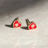 Par de aros tipo botón con forma de corazón, de plata 925 con acabado en oro de 18k, con circonia engarzada en el centro y esmalte rojo.
