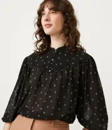 Blusa negra de chiffon con estampado de mini íconos en color crema, cuello mao, solapa frontal con botones y mangas largas abullonadas.