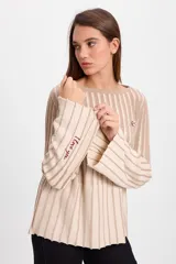 Sweater de punto con diseño de rayas verticales en dos colores, azul y crudo. Presenta cuello bote, mangas largas con terminación acampanada y un aplique decorativo en el pecho.